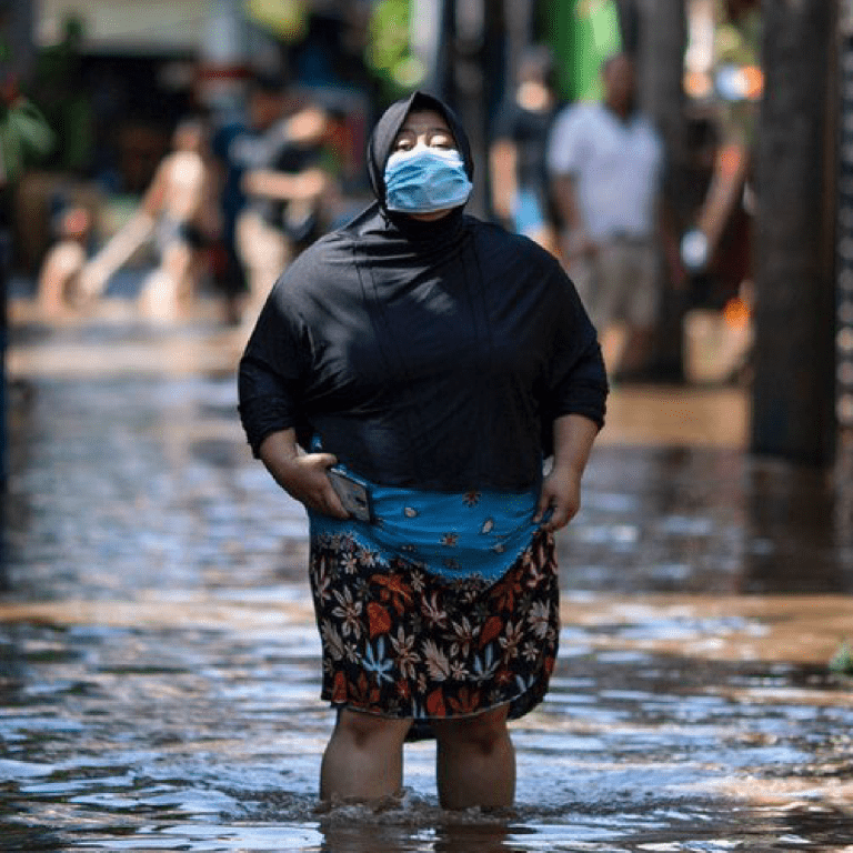 A woman walks through water in an area affected by flooding in East Jakarta, Indonesia.