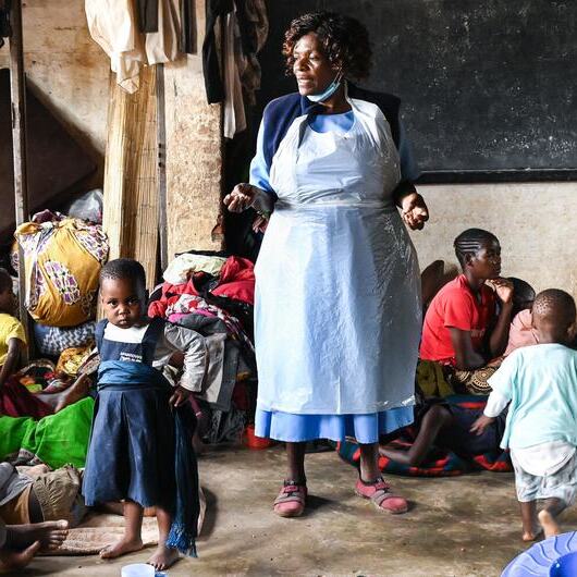 A health worker at a camp in southern Malawi talks to displaced people about cholera prevention measures
