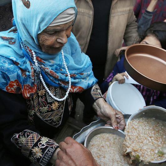 Displaced Palestinians collect food at a distribution point near a school-turned-shelter in Gaza.